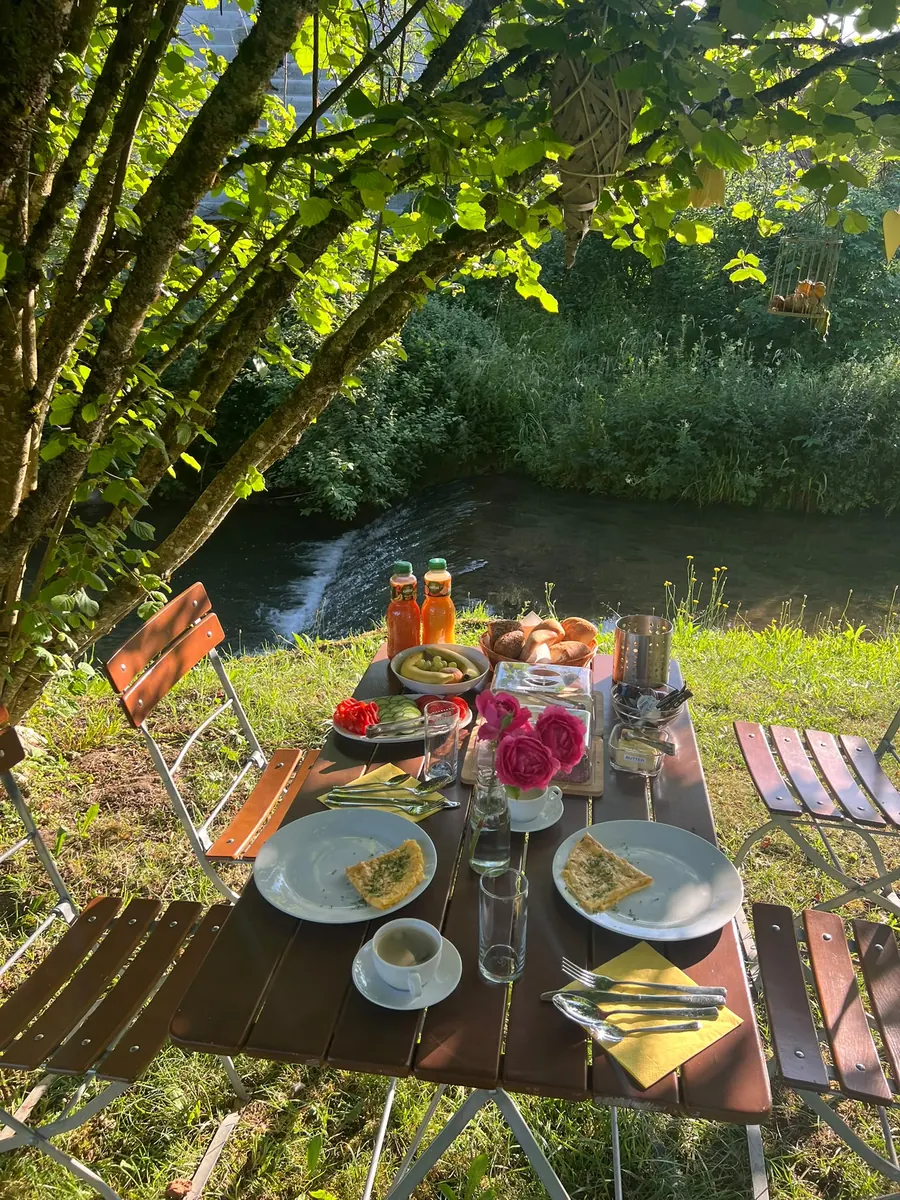 Gedeckter Frühstückstisch im Garten am Bach