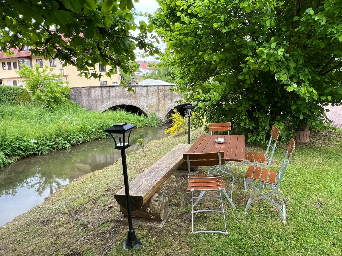 Bistrotisch mit Laterne am Ufer des Heimbachs