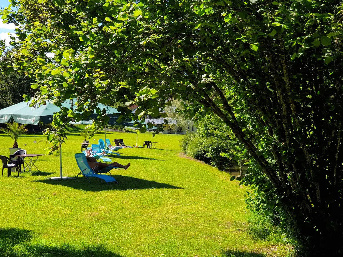 Gäste entspannen auf den Liegen im Garten am Bach