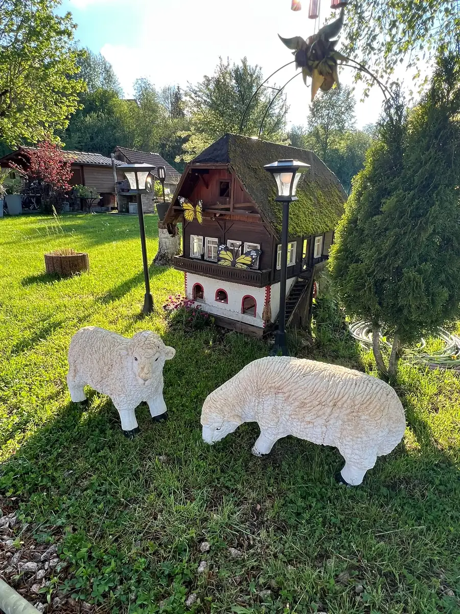 Schaf-Figuren und Deko-Häuschen auf der Gartenwiese