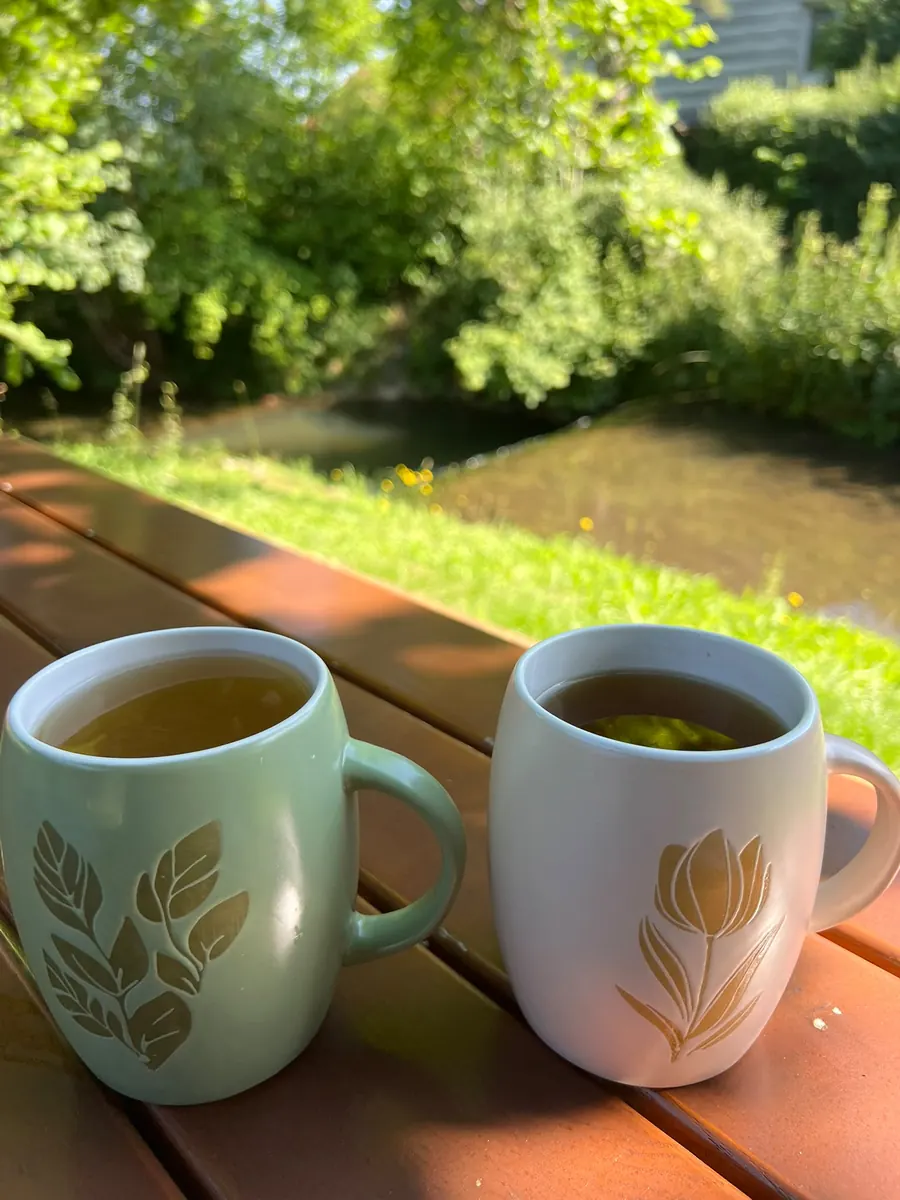 Zwei Tassen Tee auf dem Gartentisch am Bach