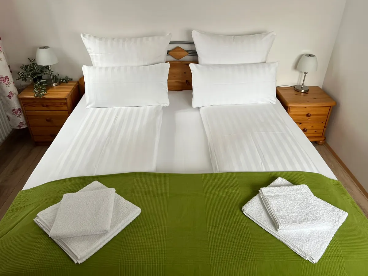 Doppelbett mit frischen Handtüchern und Nachttischlampen