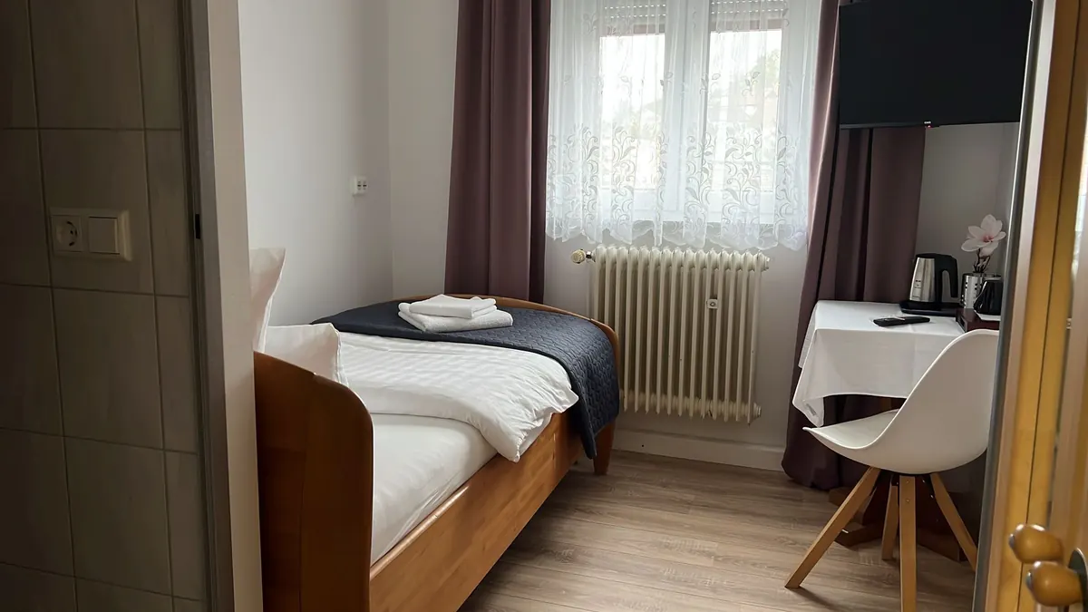 Einzelzimmer mit Schreibtisch, Stuhl und TV