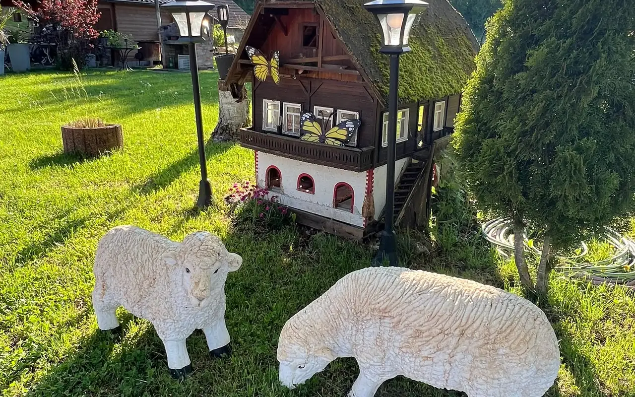 Schwarzwaldhäuschen und Schaf-Figuren auf der Gartenwiese