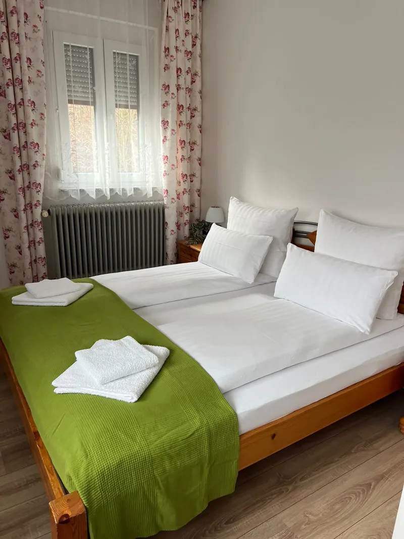 Doppelzimmer mit frisch bezogenem Bett und grüner Tagesdecke